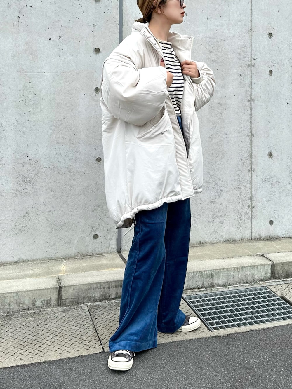 ホワイト系のダウンジャケット/コート、ブルー系のパンツ、ブラック系のスニーカーを着用したレディースの秋コーディネートの2枚目の写真