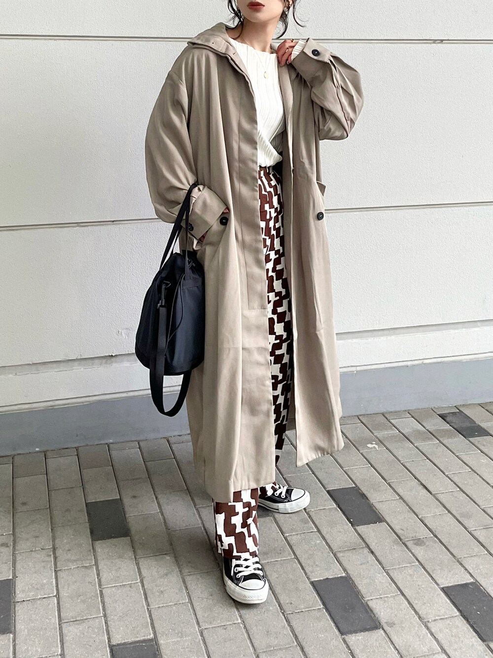 ベージュ系のトレンチコート、ブラウン系のパンツ、ブラック系のバッグを着用したレディースの冬コーディネートの4枚目の写真