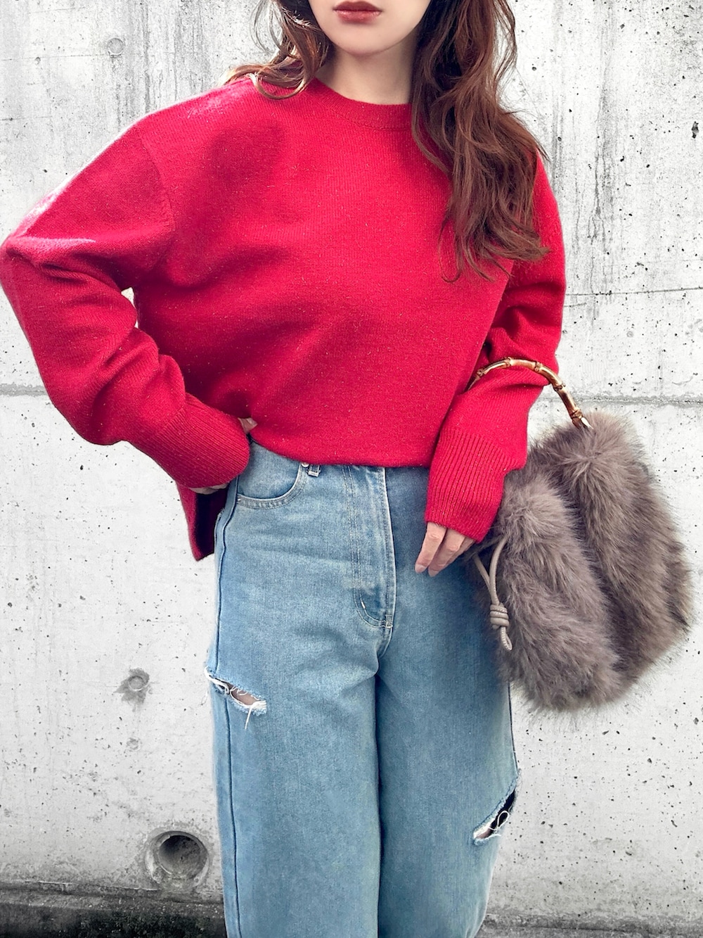 レッド系のニット/セーター、ブルー系のデニムパンツ、ブラウン系のハンドバッグを着用したレディースの冬コーディネートの3枚目の写真