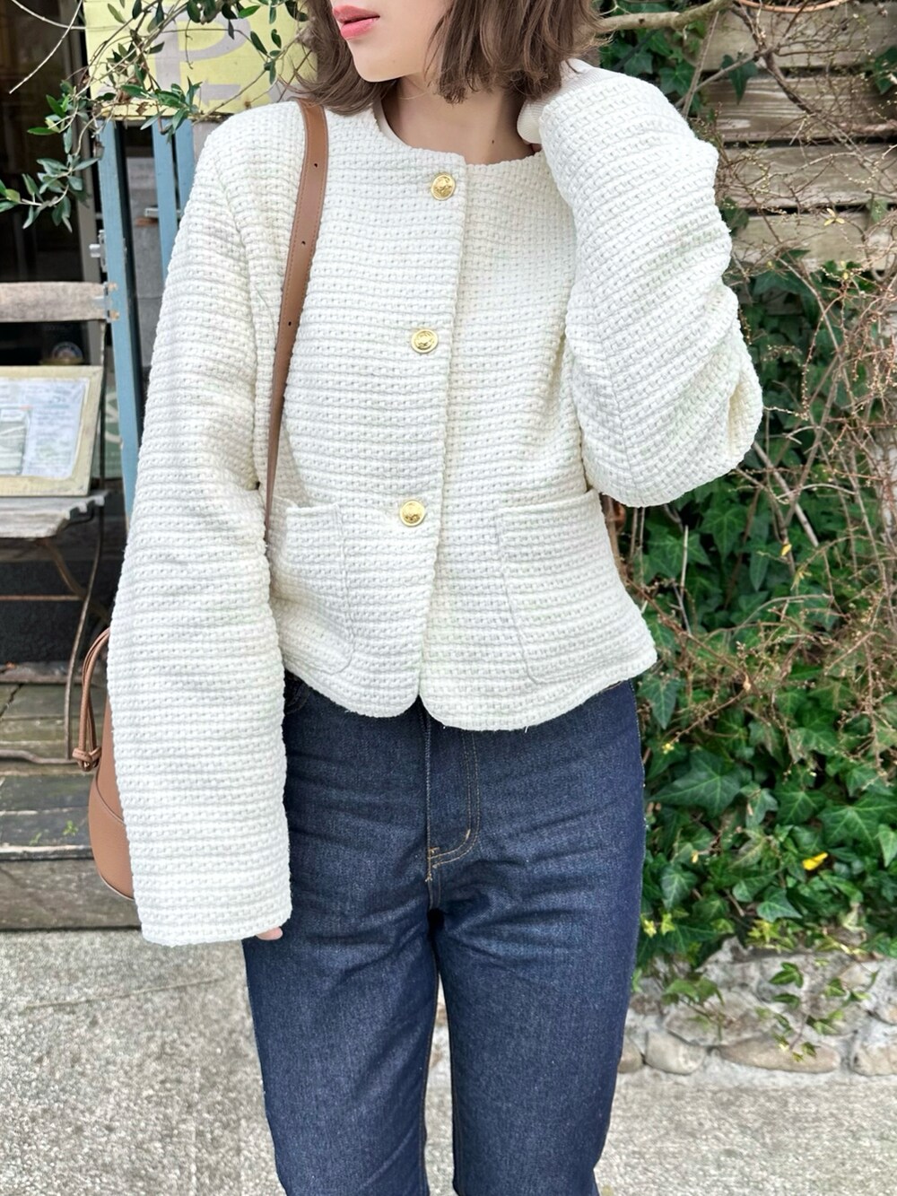 ホワイト系のノーカラージャケット、ブルー系のデニムパンツ、ホワイト系のトップスを着用したレディースの冬コーディネートの3枚目の写真