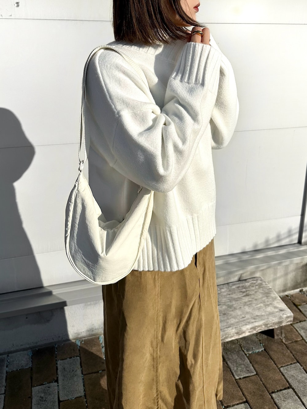 ホワイト系のニット/セーター、ホワイト系のショルダーバッグ、ベージュ系のスニーカーを着用したレディースの冬コーディネートの2枚目の写真