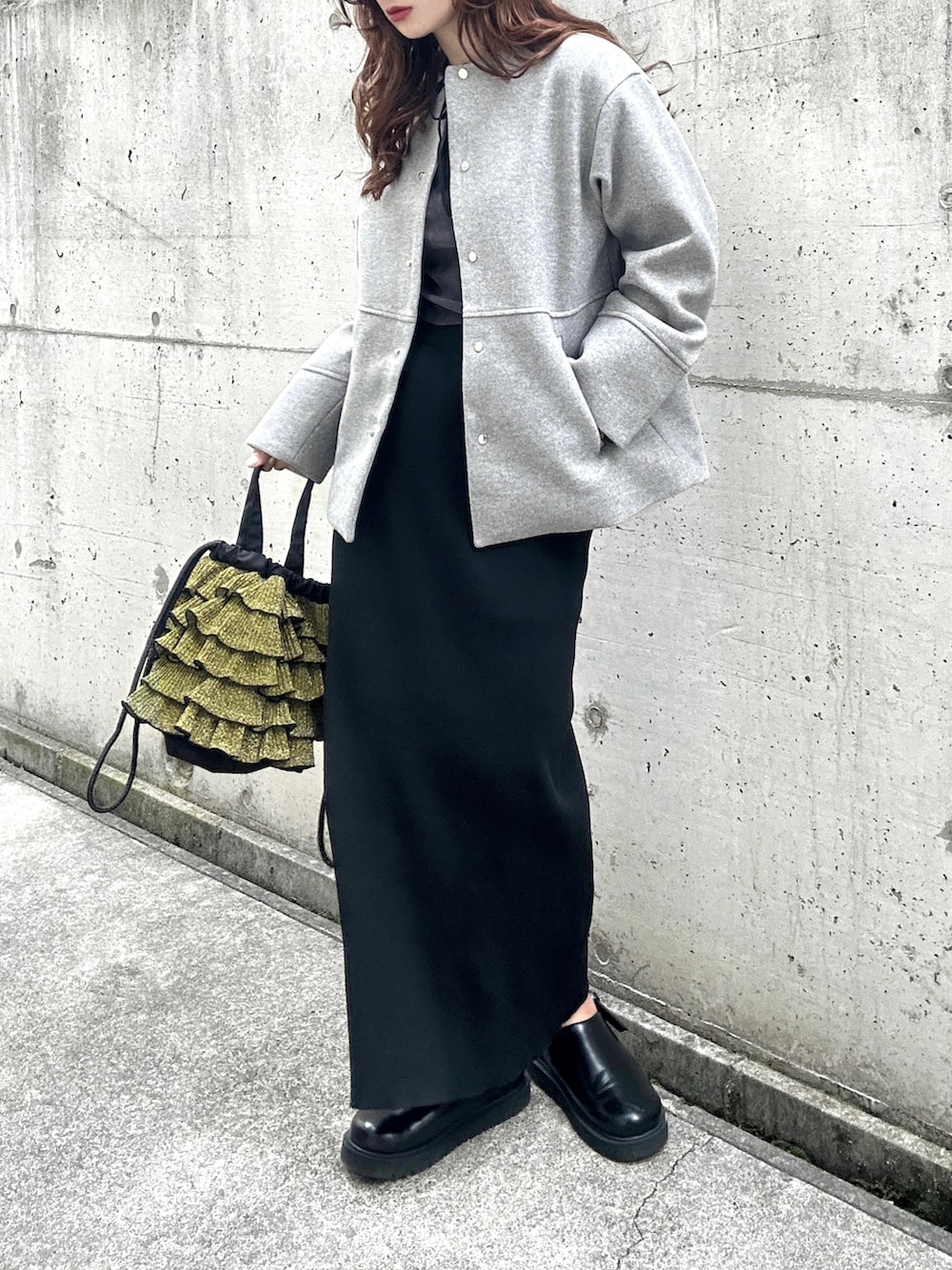 グレー系のTシャツ/カットソー、グレー系のノーカラーコート、ブラック系のスカートを着用したレディースの秋コーディネートの3枚目の写真