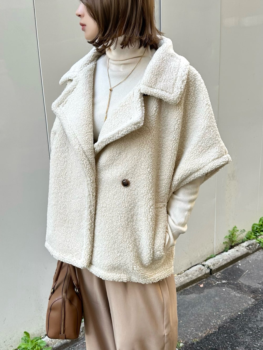 ホワイト系のステンカラーコート、ベージュ系のその他パンツ、ホワイト系のニット/セーターを着用したレディースの冬コーディネートの3枚目の写真