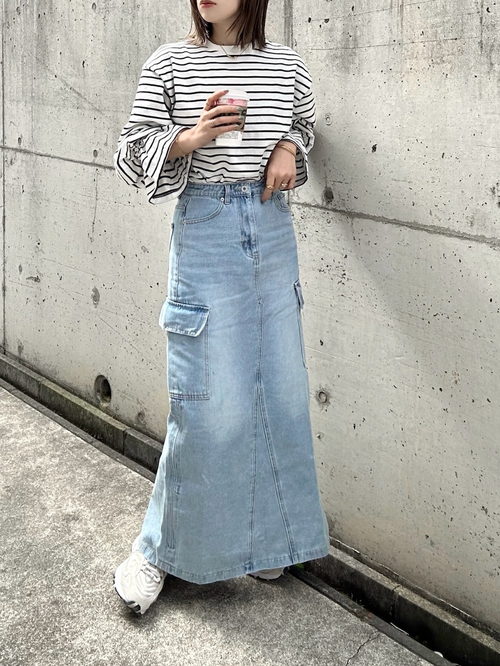 ホワイト系のTシャツ/カットソー、ブルー系のデニムスカート、ベージュ系のスニーカーを着用したレディースの春コーディネートの2枚目の写真