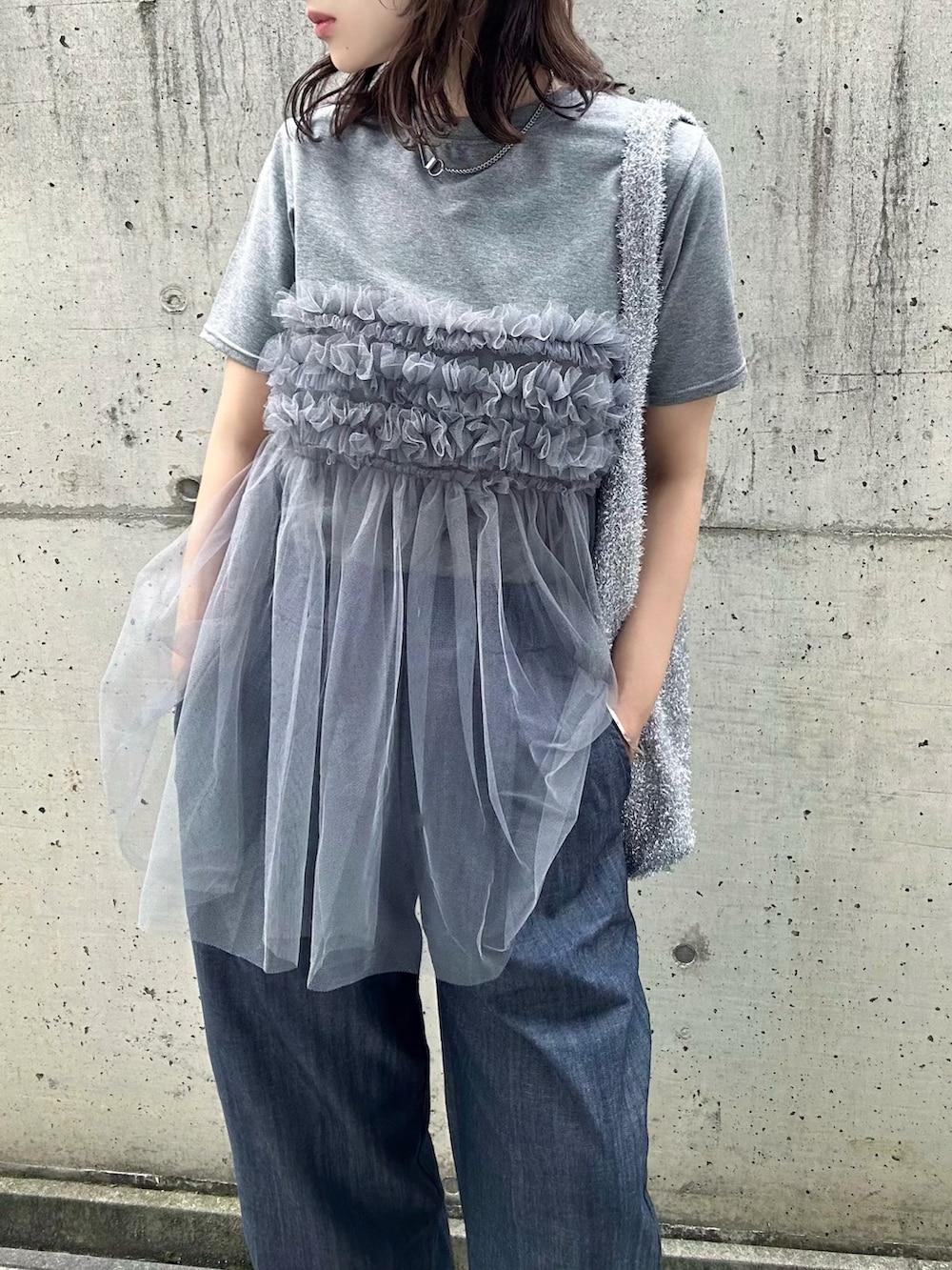 グレー系のTシャツ/カットソー、シルバー系のショルダーバッグ、ブルー系のデニムパンツを着用したレディースの夏コーディネートの4枚目の写真
