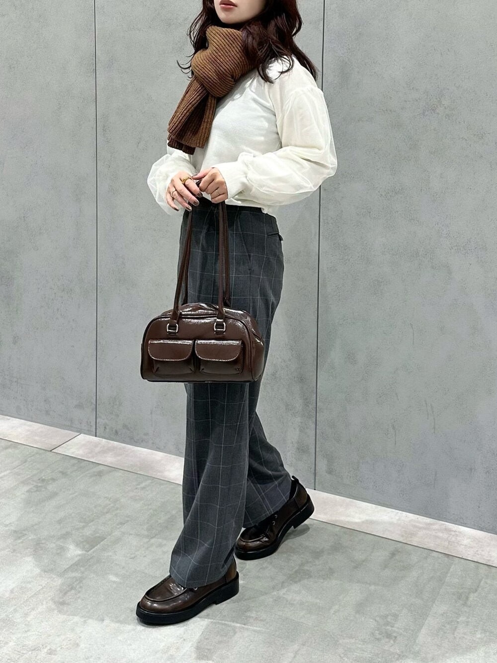 ホワイト系のニット/セーター、グレー系のパンツ、ブラウン系のショルダーバッグを着用したレディースの冬コーディネートの2枚目の写真