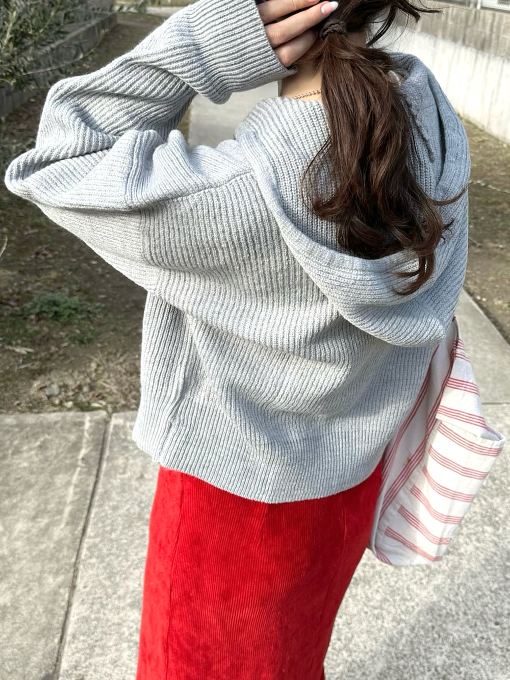 グレー系のパーカー、レッド系のスカート、ベージュ系のスニーカーを着用したレディースの冬コーディネートの5枚目の写真