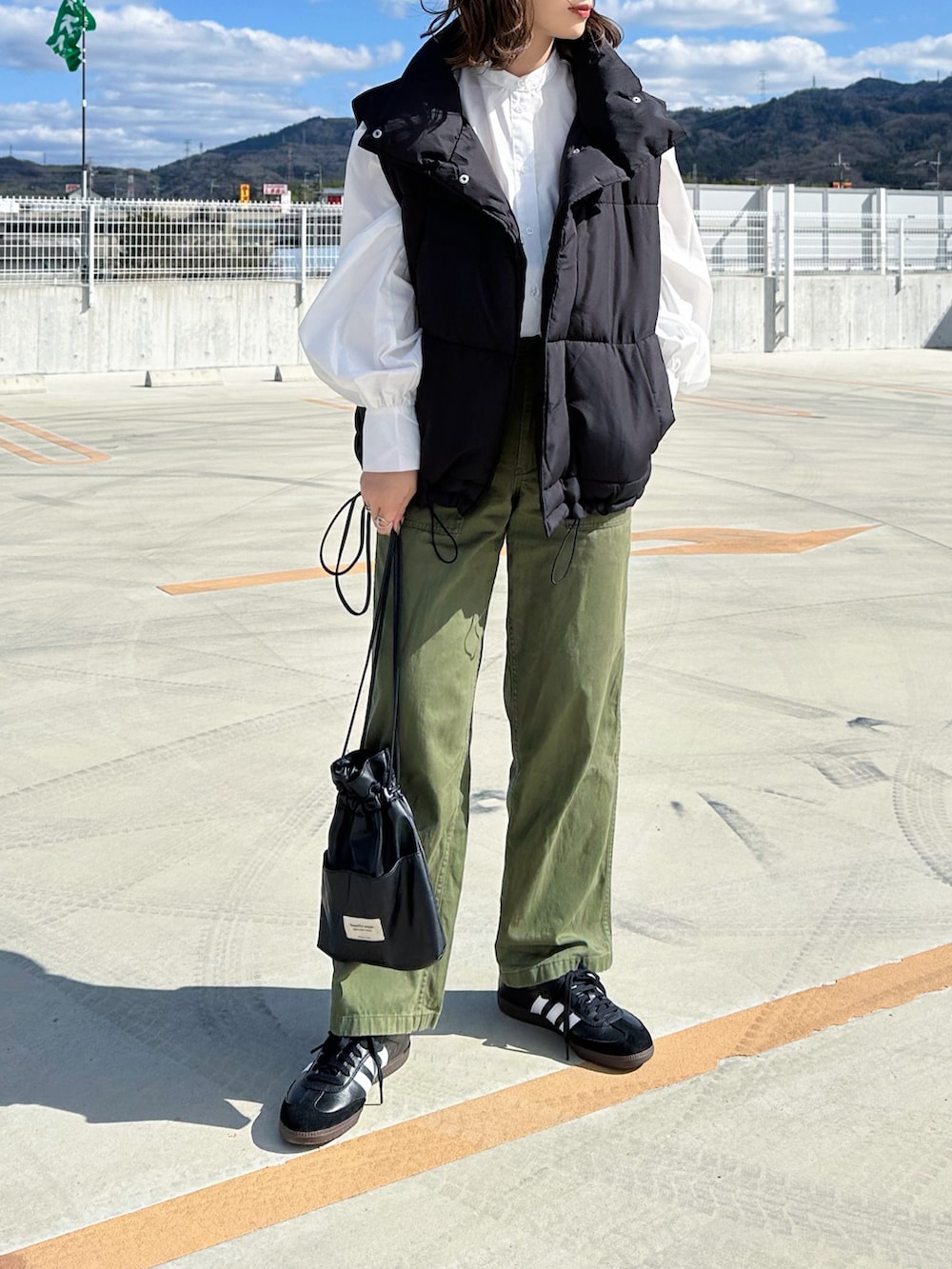 ホワイト系のシャツ/ブラウス、グリーン系のパンツ、ブラック系のショルダーバッグを着用したレディースの春コーディネートの2枚目の写真