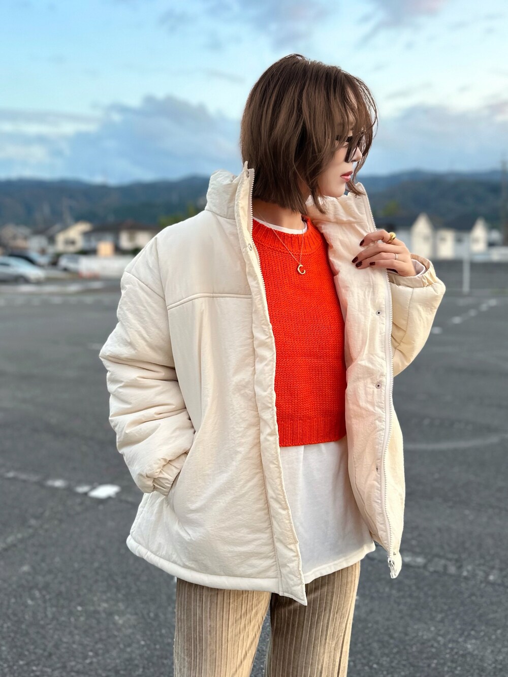 ホワイト系のブルゾン、オレンジ系のニット/セーター、ホワイト系のTシャツ/カットソーを着用したレディースの秋コーディネートの3枚目の写真