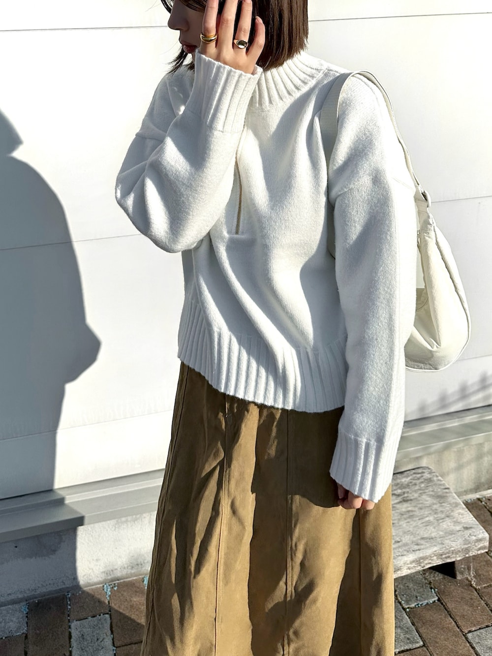 ホワイト系のニット/セーター、ホワイト系のショルダーバッグ、ベージュ系のスニーカーを着用したレディースの冬コーディネートの3枚目の写真