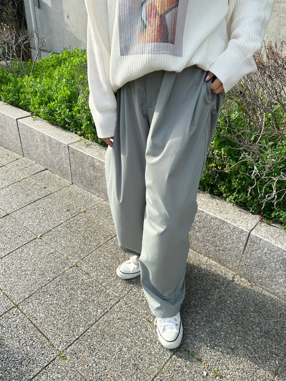 ホワイト系のニット/セーター、グリーン系のチノパンツ、ホワイト系のスニーカーを着用したレディースの春コーディネートの5枚目の写真