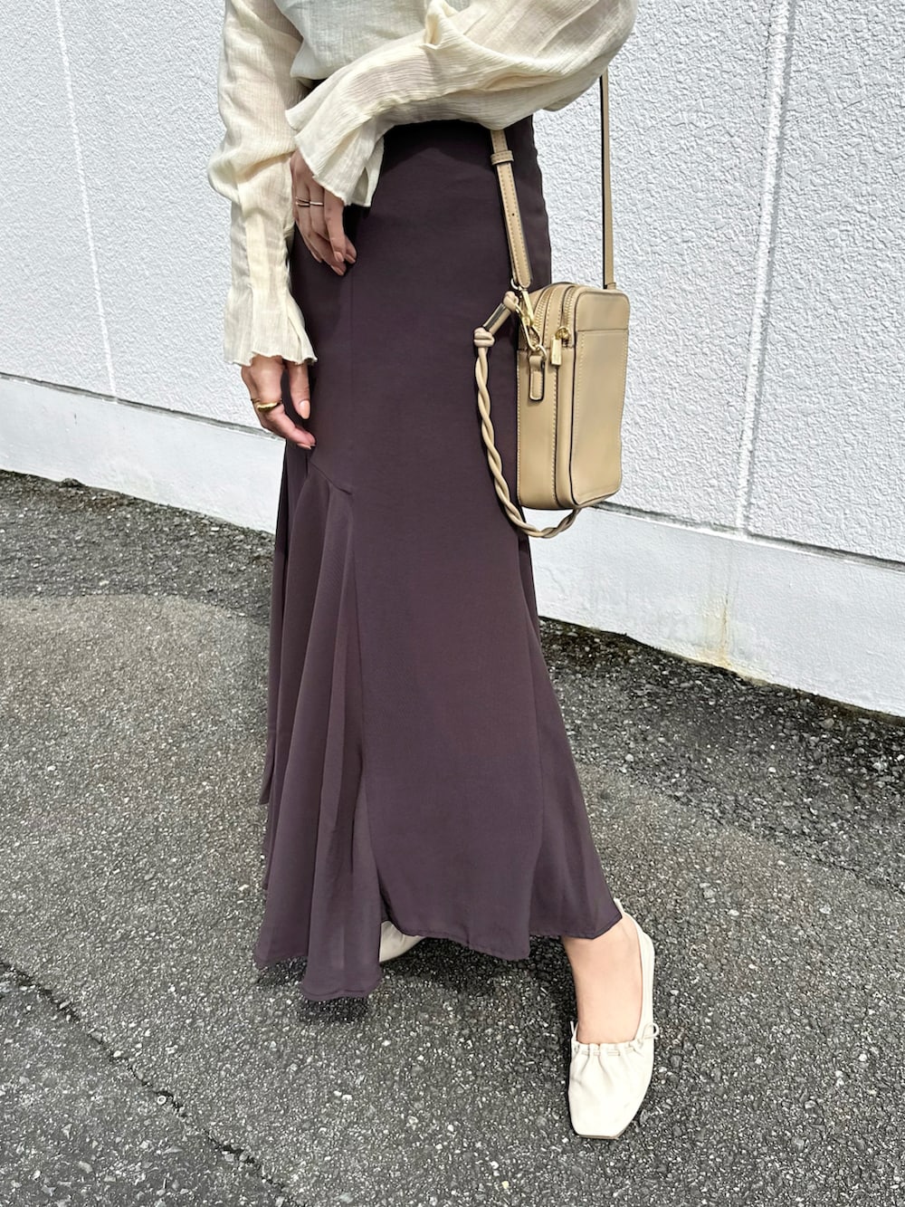 ブラウン系のスカート、ベージュ系のTシャツ/カットソー、ベージュ系のバッグを着用したレディースの秋コーディネートの4枚目の写真