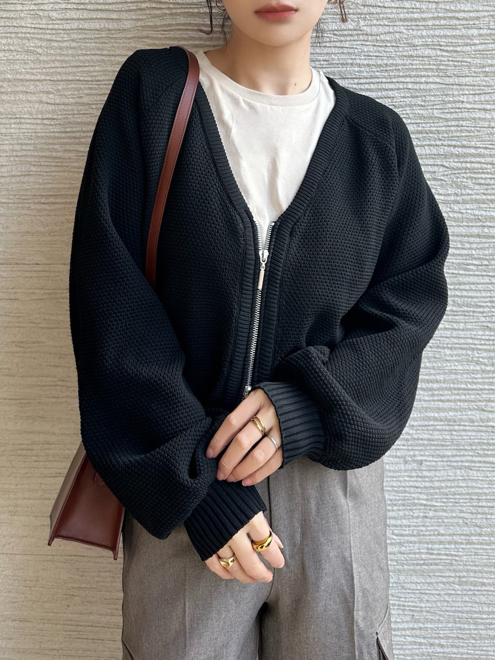 ブラック系のニット/セーター、ベージュ系のタンクトップ、ブラウン系のカーゴパンツを着用したレディースの春コーディネートの2枚目の写真