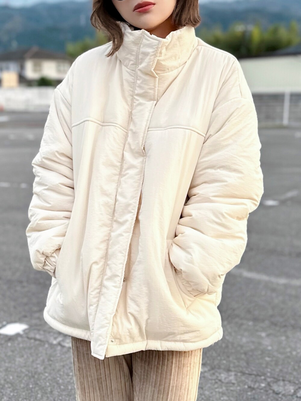 ホワイト系のブルゾン、オレンジ系のニット/セーター、ホワイト系のTシャツ/カットソーを着用したレディースの秋コーディネートの4枚目の写真