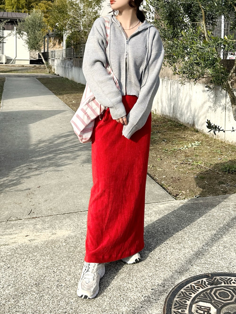 グレー系のパーカー、レッド系のスカート、ベージュ系のスニーカーを着用したレディースの冬コーディネートの3枚目の写真