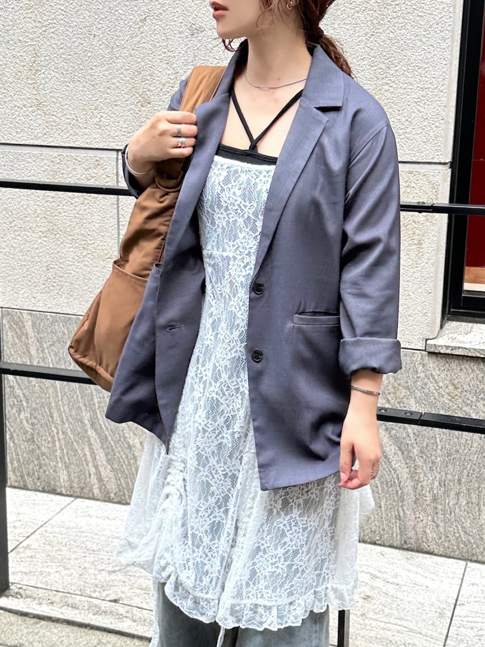 ホワイト系のチュニック、グレー系のテーラードジャケット、ブラック系のキャミソールを着用したレディースの春コーディネートの4枚目の写真