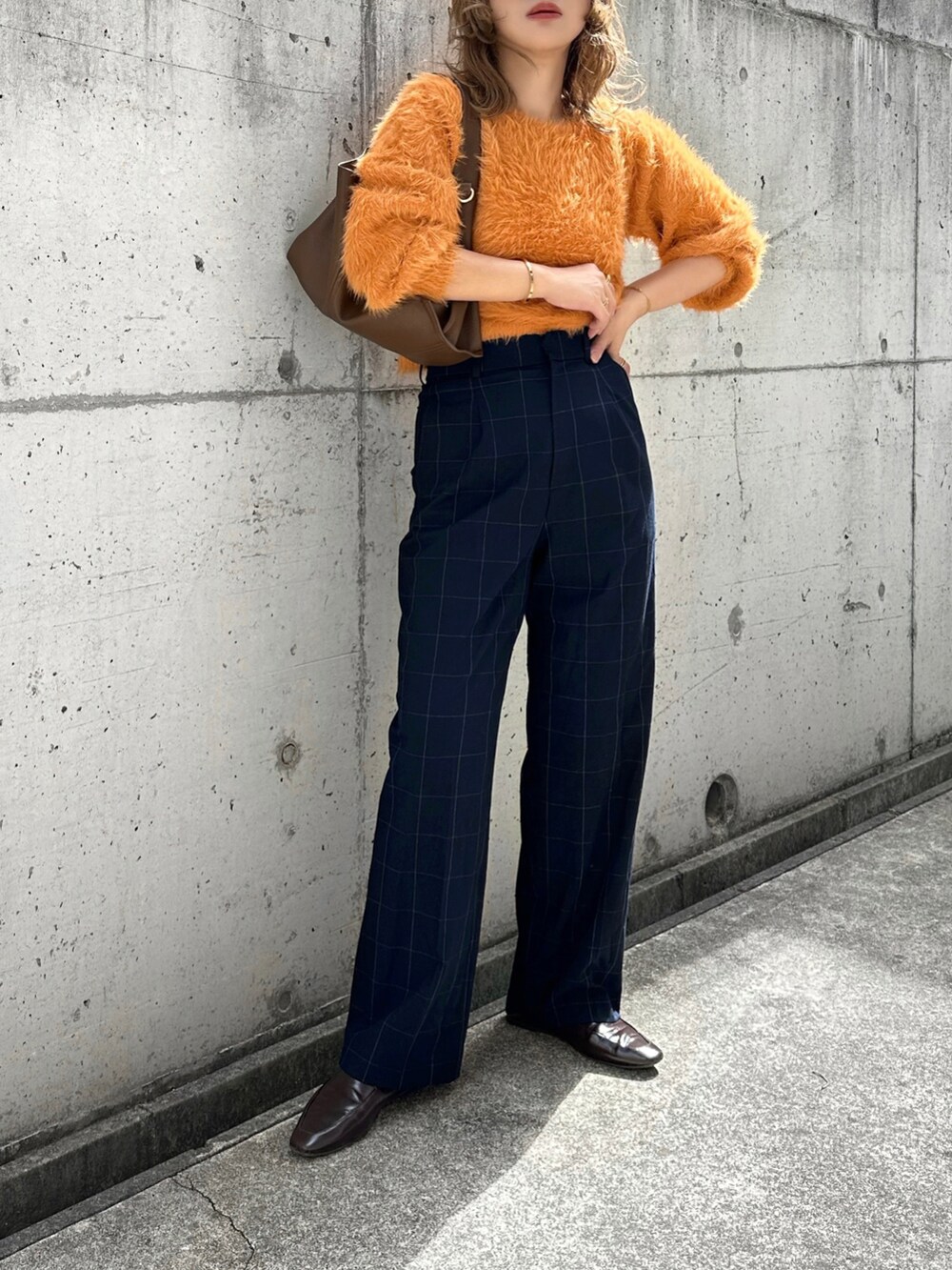 オレンジ系のニット/セーター、ブルー系のパンツ、ブラウン系のバッグを着用したレディースの秋コーディネートの3枚目の写真