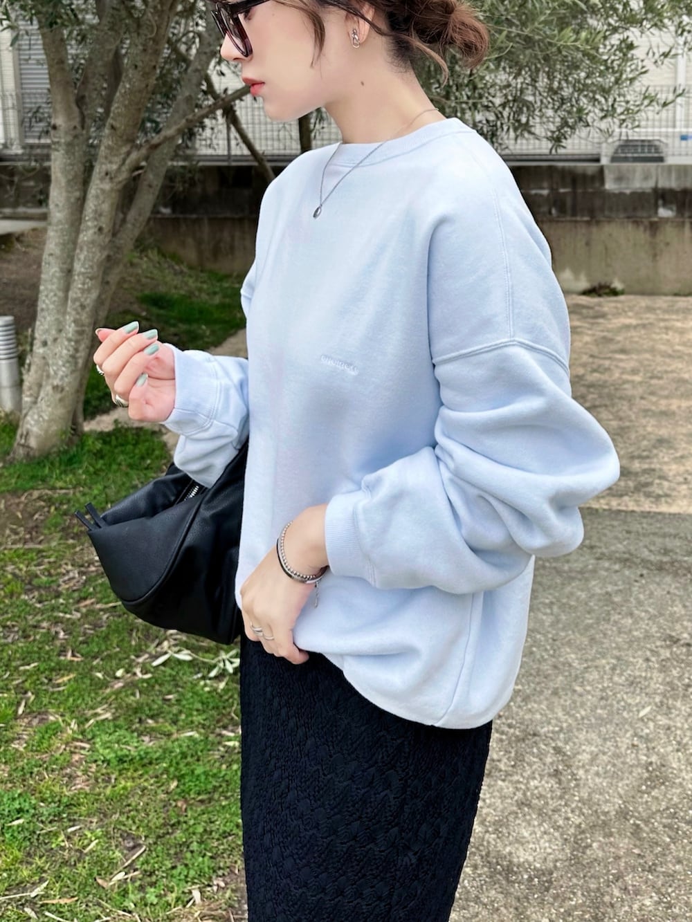 ブルー系のスウェット、ブラック系のハンドバッグ、ブラック系のスニーカーを着用したレディースの春コーディネートの4枚目の写真