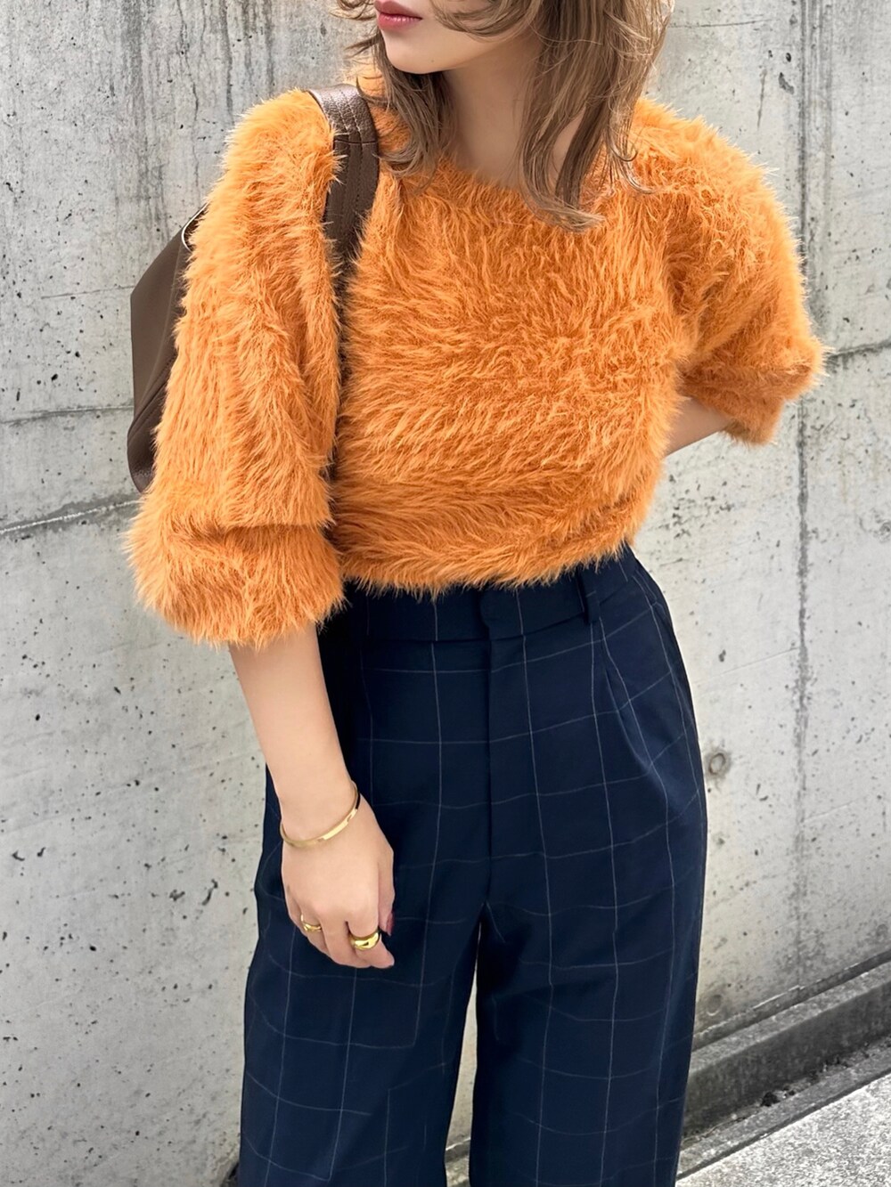 オレンジ系のニット/セーター、ブルー系のパンツ、ブラウン系のバッグを着用したレディースの秋コーディネートの4枚目の写真