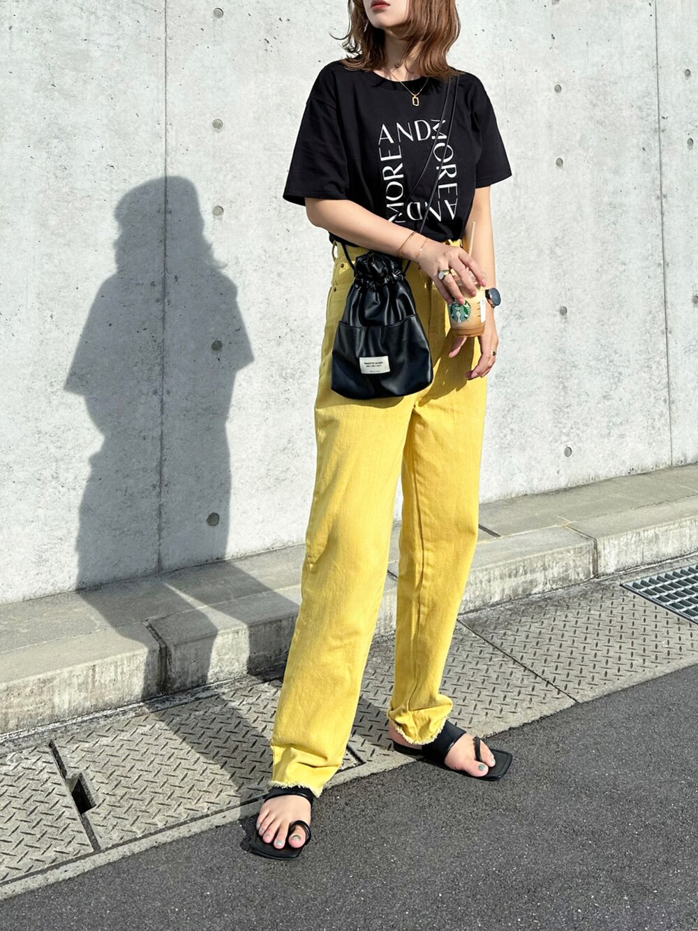 ブラック系のTシャツ/カットソー、イエロー系のデニムパンツ、ブラック系のショルダーバッグを着用したレディースの夏コーディネートの2枚目の写真