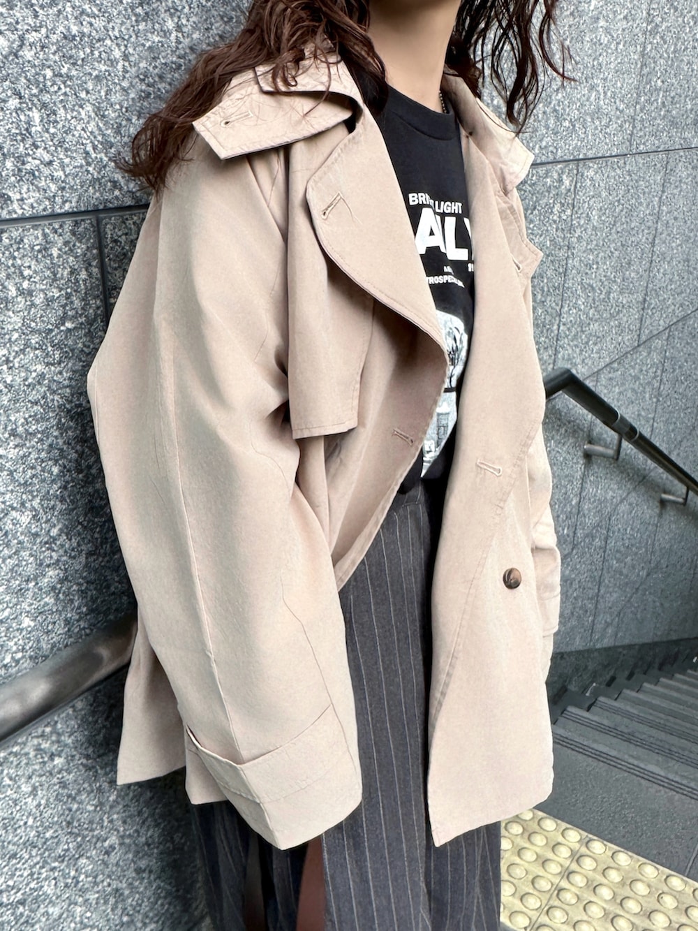 ベージュ系のトレンチコート、ブラック系のTシャツ/カットソー、グレー系のその他パンツを着用したレディースの春コーディネートの3枚目の写真