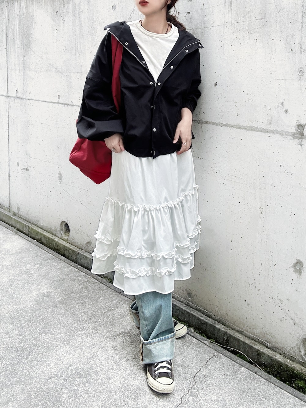 ブラック系のマウンテンパーカー、ホワイト系のスカート、ホワイト系のTシャツ/カットソーを着用したレディースの春コーディネートの2枚目の写真