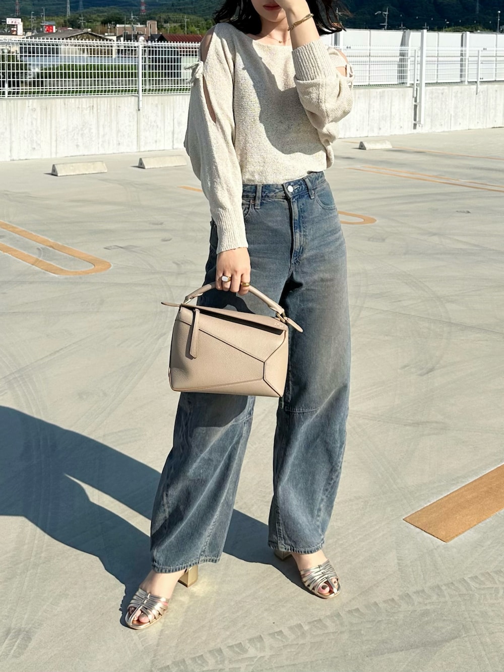 ベージュ系のニット/セーター、ブルー系のデニムパンツ、ベージュ系のショルダーバッグを着用したレディースの夏コーディネートの2枚目の写真