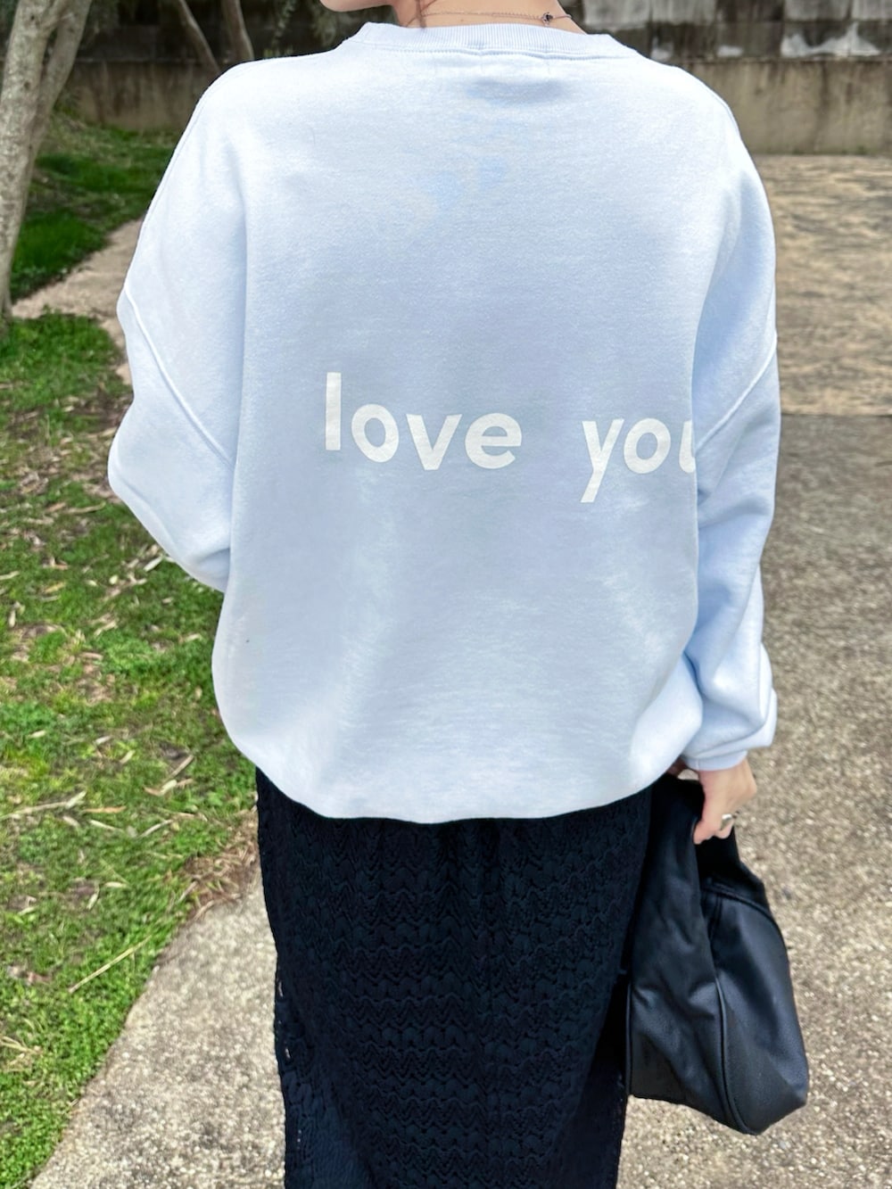 ブルー系のスウェット、ブラック系のハンドバッグ、ブラック系のスニーカーを着用したレディースの春コーディネートの3枚目の写真