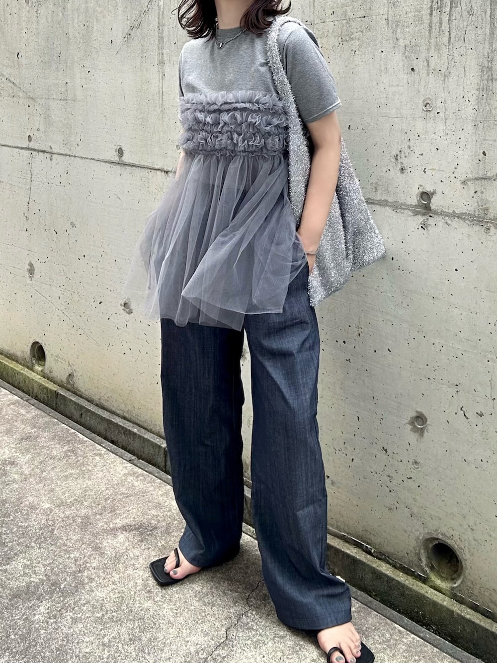 グレー系のTシャツ/カットソー、シルバー系のショルダーバッグ、ブルー系のデニムパンツを着用したレディースの夏コーディネートの2枚目の写真