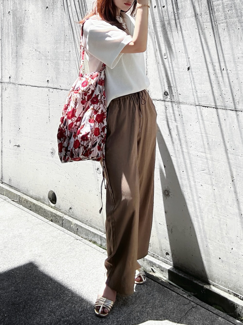ホワイト系のTシャツ/カットソー、ブラウン系のスラックス、ゴールド系のサンダルを着用したレディースの夏コーディネートの2枚目の写真