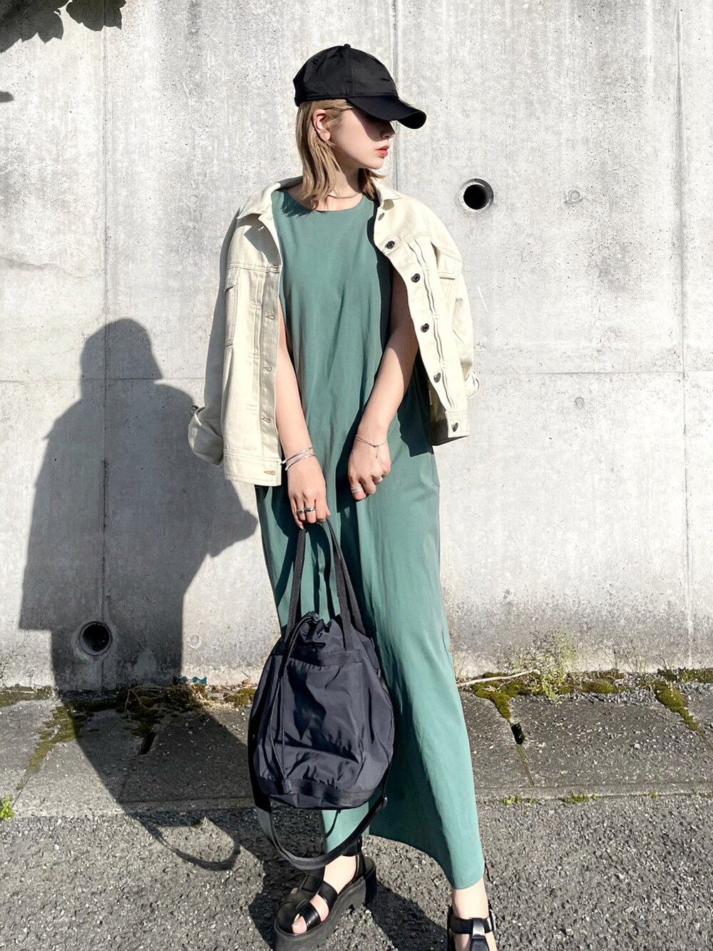 グリーン系のワンピース、ブラック系のバッグ、ブラック系のサンダルを着用したレディースの春コーディネートの3枚目の写真