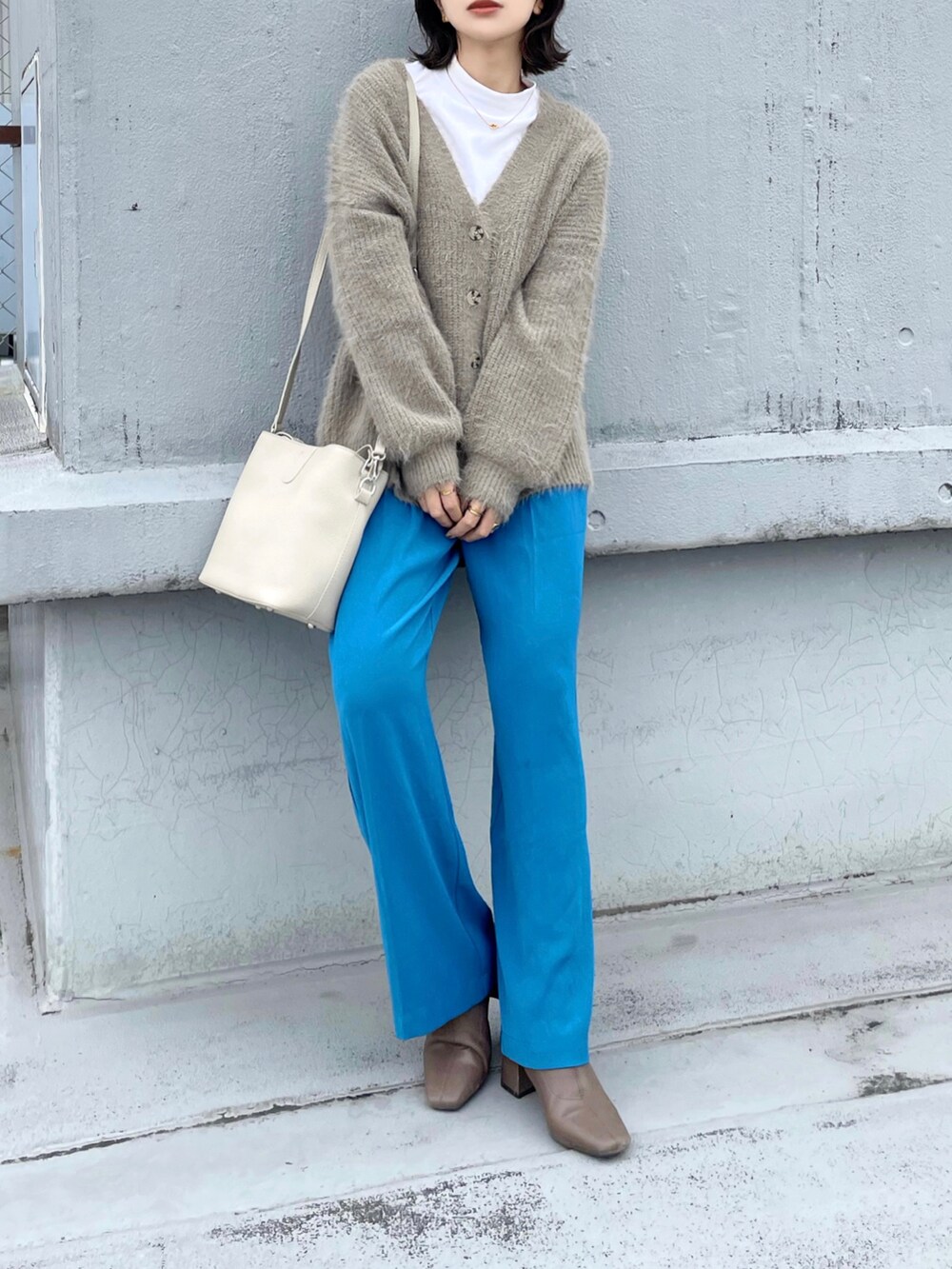 ベージュ系のカーディガン/ボレロ、ブルー系のスラックス、ベージュ系のハンドバッグを着用したレディースの冬コーディネートの2枚目の写真