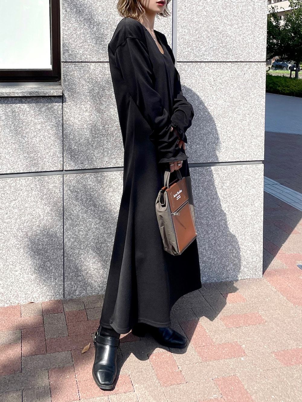 ブラック系のワンピース、ベージュ系のカーディガン/ボレロ、ブラウン系のバッグを着用したレディースの秋コーディネートの4枚目の写真