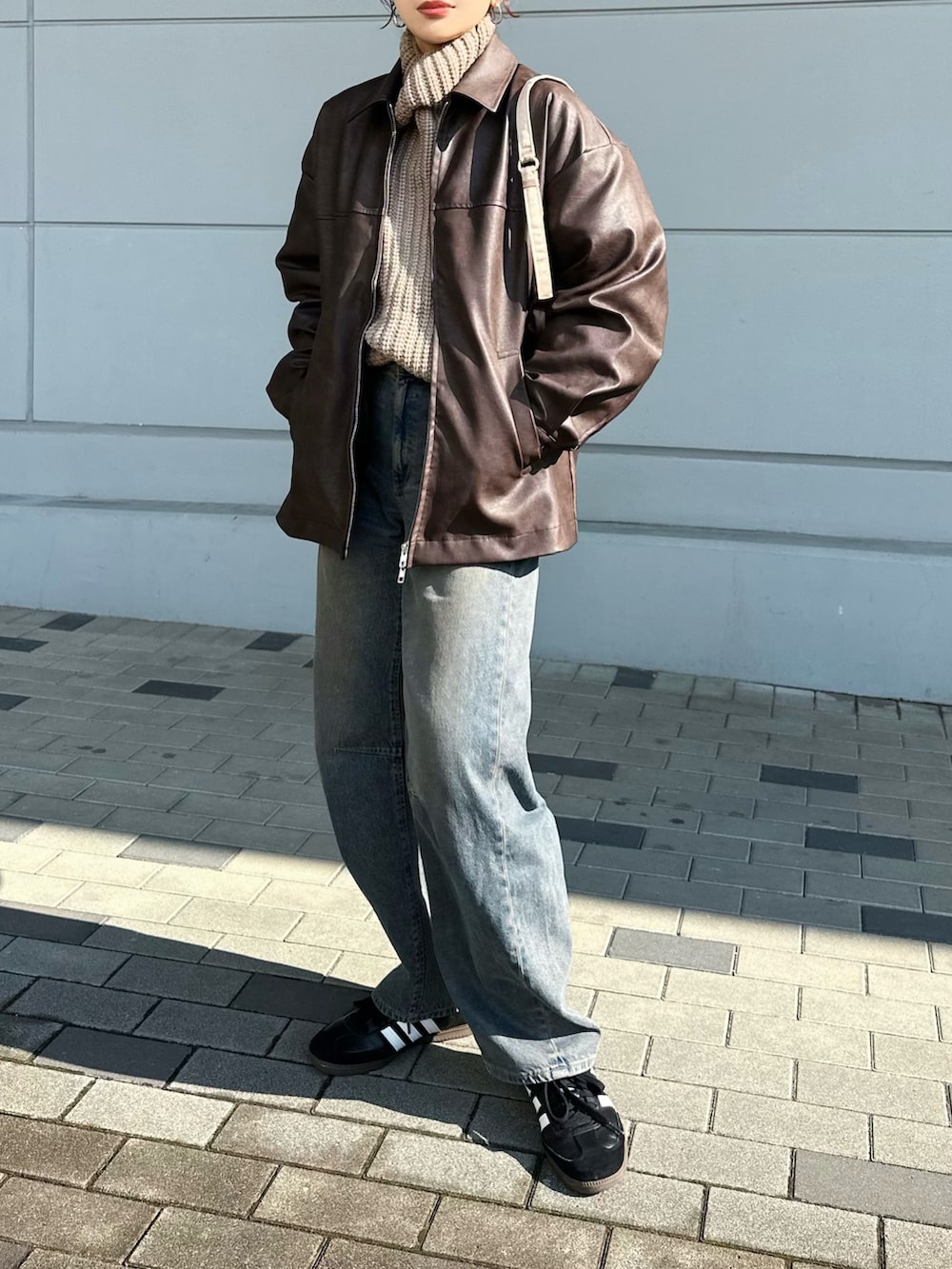 ブラウン系のブルゾン、ベージュ系のニット/セーター、ブルー系のデニムパンツを着用したレディースの冬コーディネートの2枚目の写真