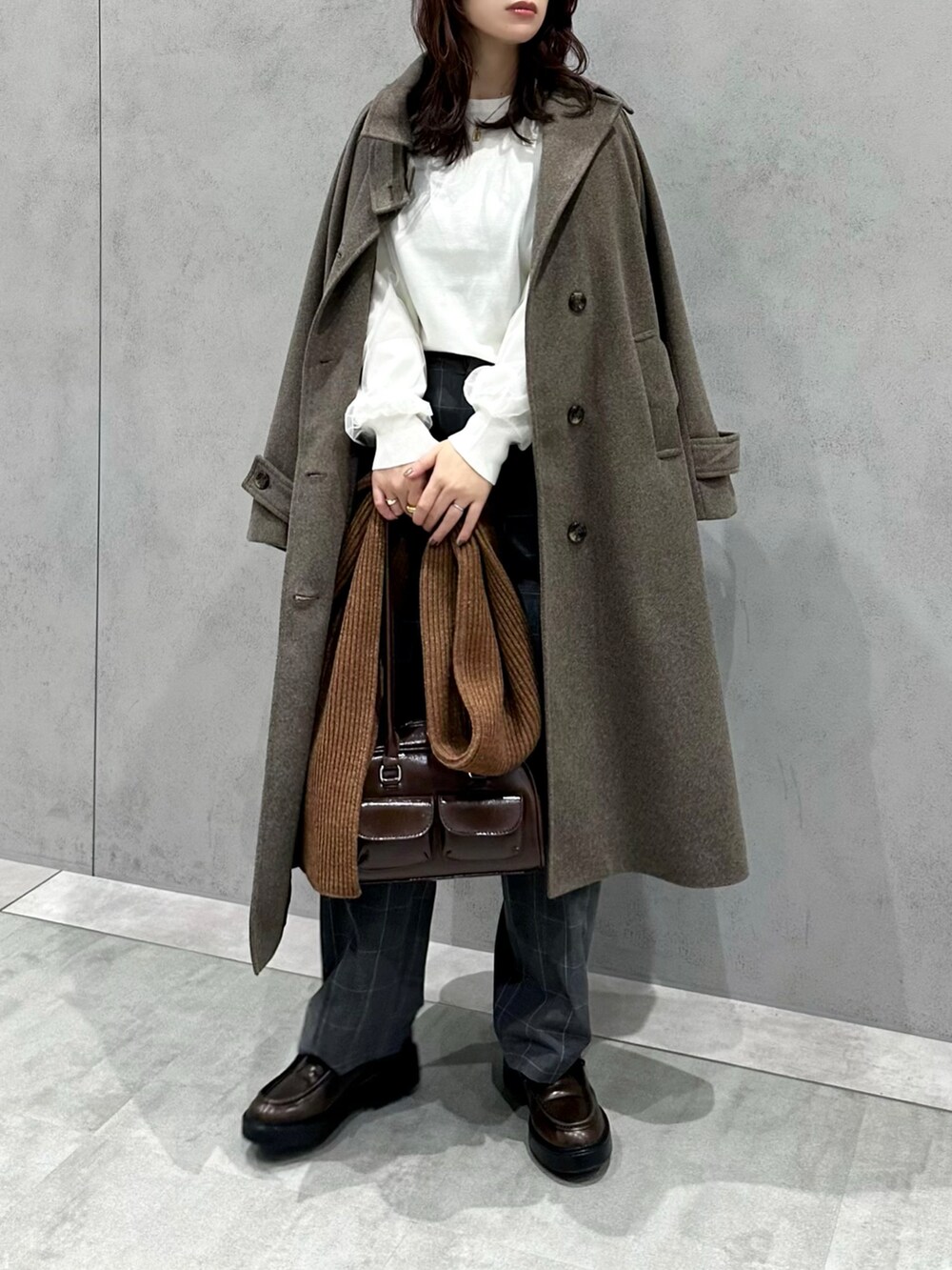 ホワイト系のニット/セーター、グレー系のパンツ、ブラウン系のショルダーバッグを着用したレディースの冬コーディネートの3枚目の写真
