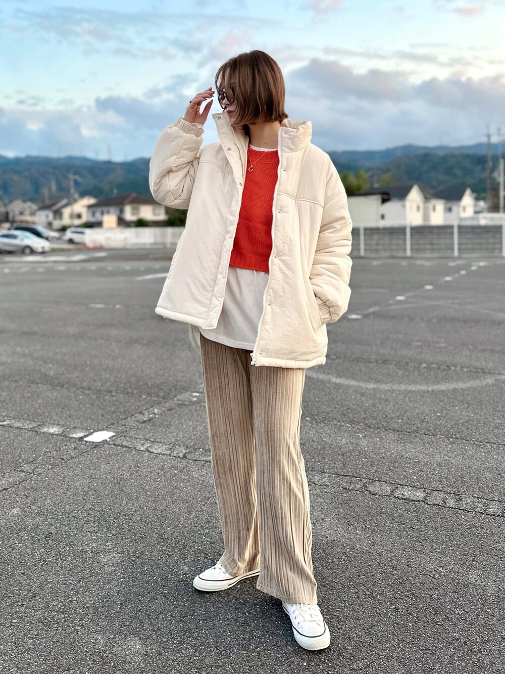 ホワイト系のブルゾン、オレンジ系のニット/セーター、ホワイト系のTシャツ/カットソーを着用したレディースの秋コーディネートの2枚目の写真