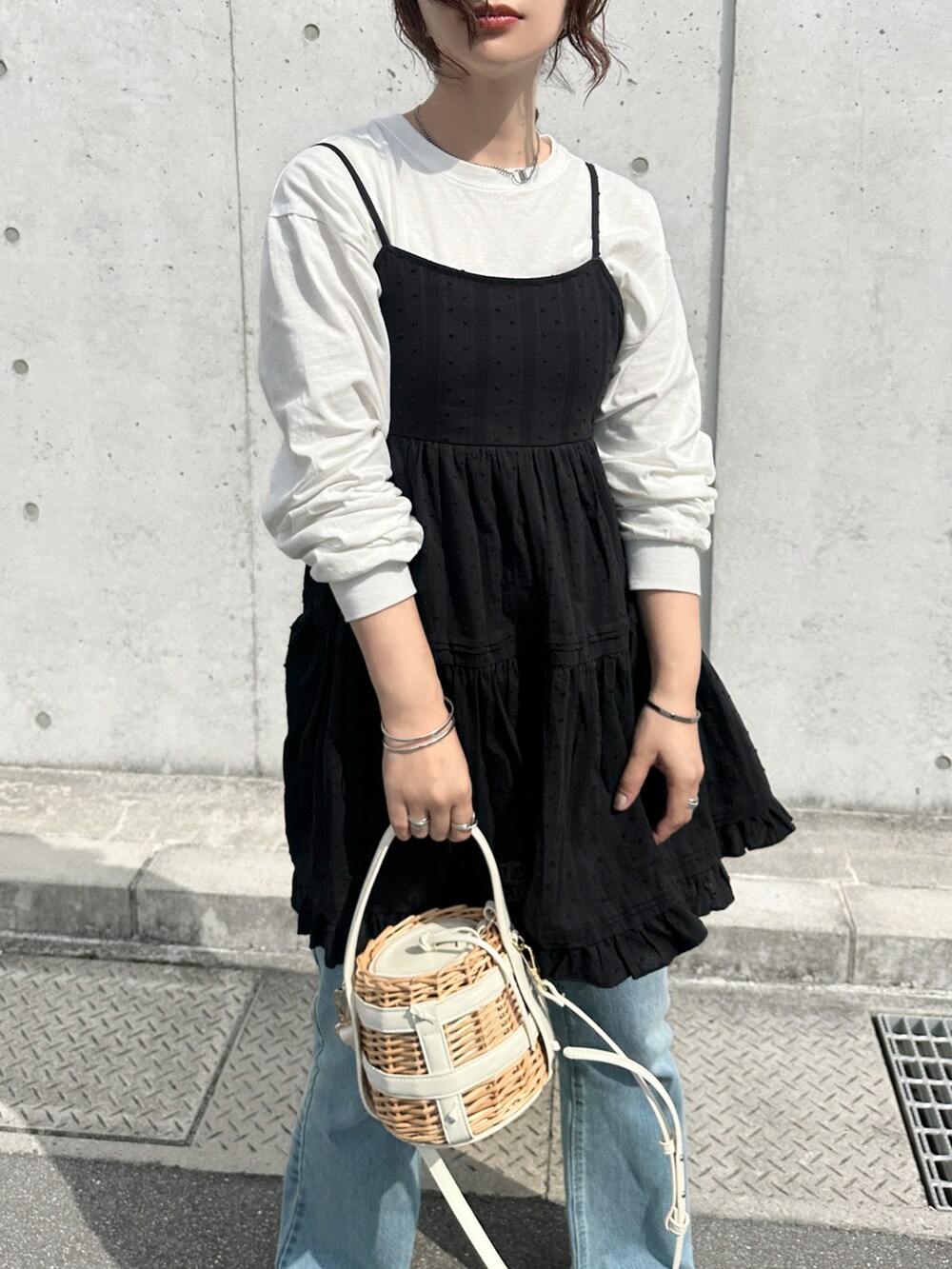 ブラック系のチュニック、ブルー系のデニムパンツを着用したレディースの春コーディネートの4枚目の写真
