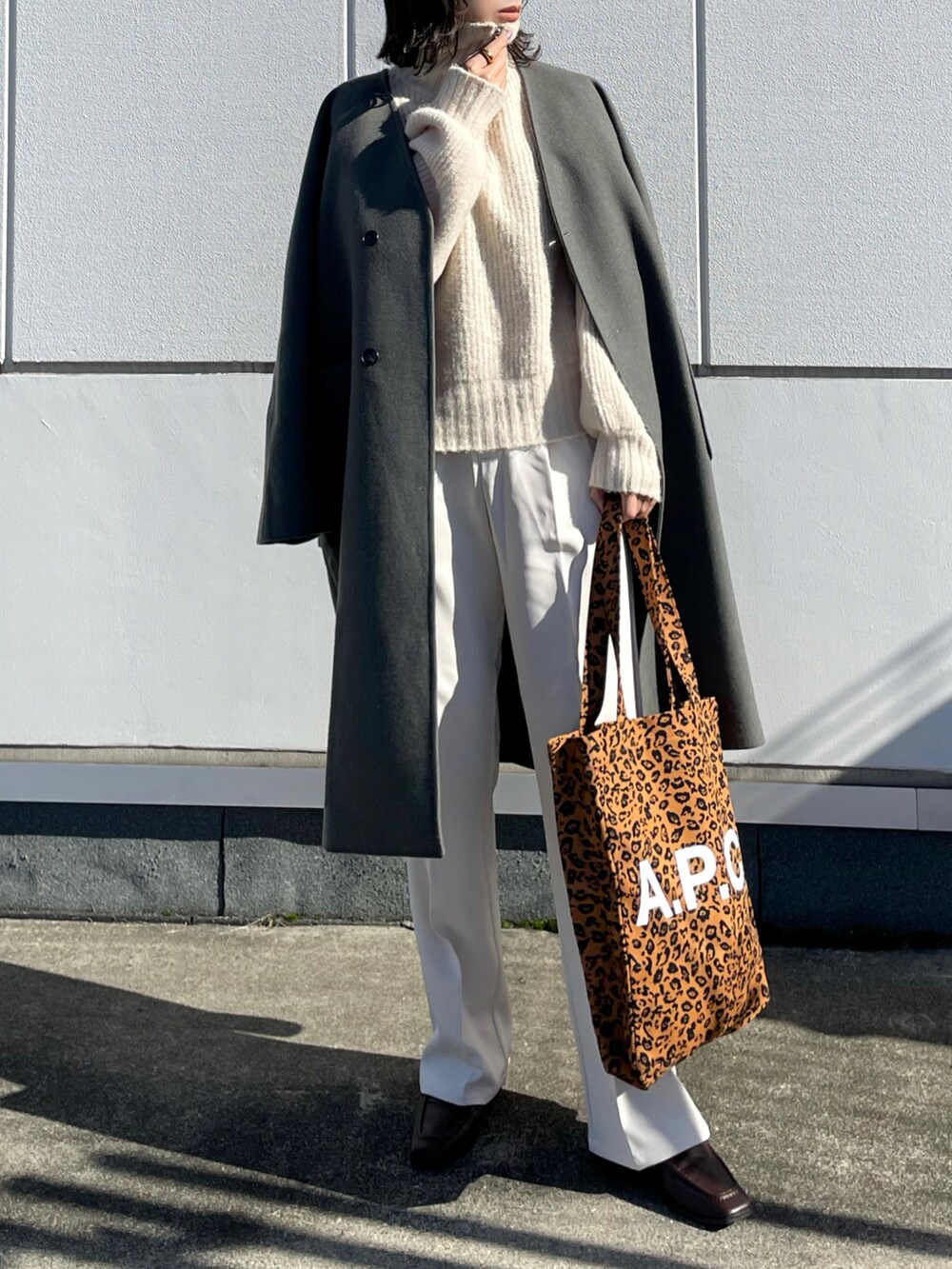 グリーン系のノーカラージャケット、ホワイト系のニット/セーター、ホワイト系のスラックスを着用したレディースの秋コーディネートの2枚目の写真