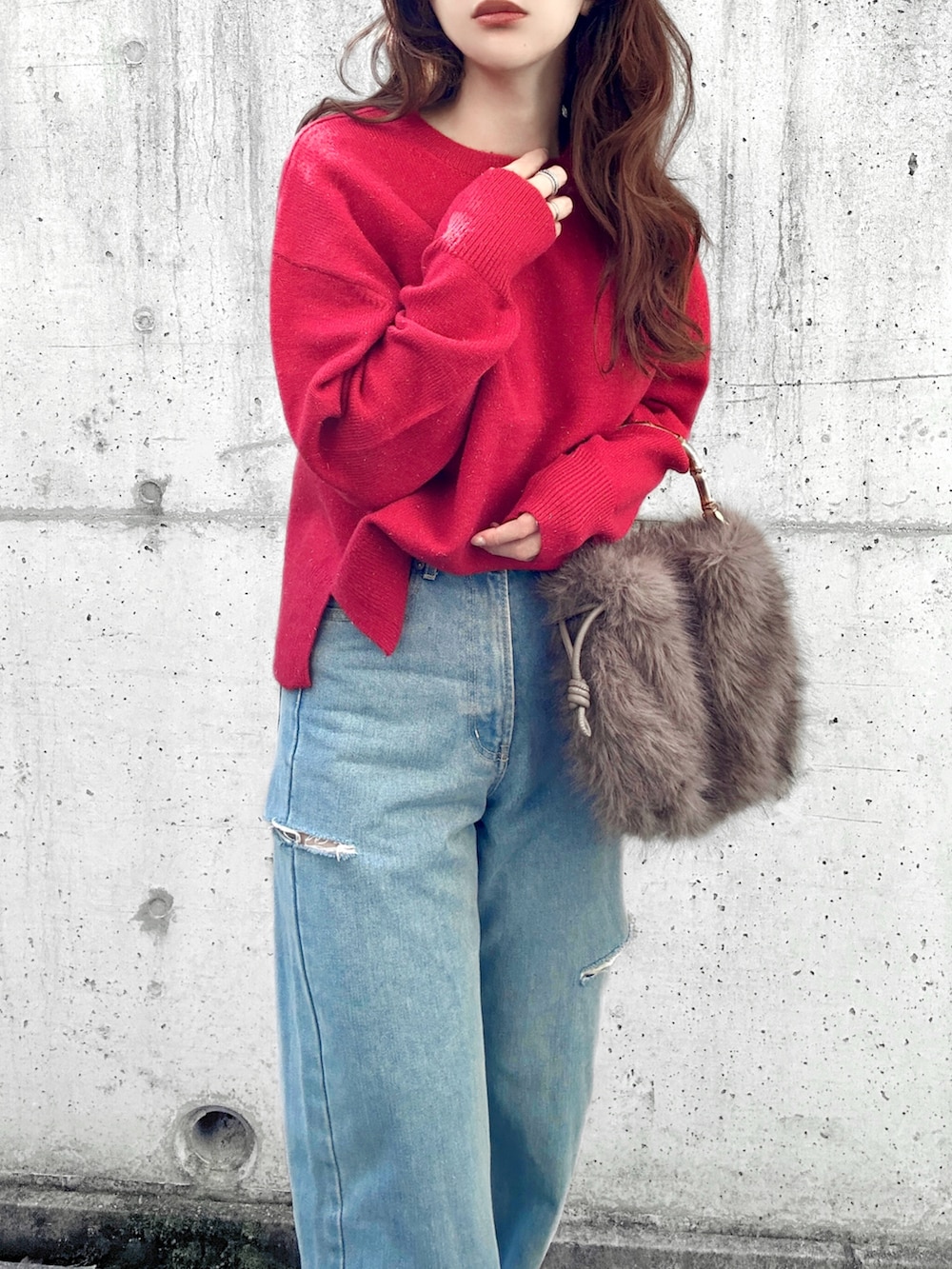 レッド系のニット/セーター、ブルー系のデニムパンツ、ブラウン系のハンドバッグを着用したレディースの冬コーディネートの2枚目の写真