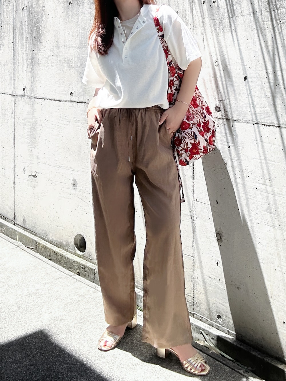 ホワイト系のTシャツ/カットソー、ブラウン系のスラックス、ゴールド系のサンダルを着用したレディースの夏コーディネートの3枚目の写真