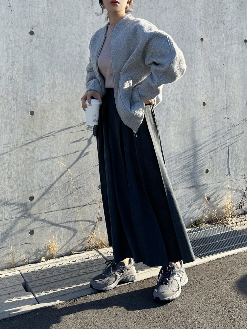 ピンク系のニット/セーター、グレー系のスカート、グレー系のスニーカーを着用したレディースの冬コーディネートの2枚目の写真