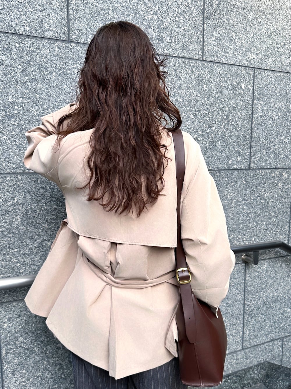 ベージュ系のトレンチコート、ブラック系のTシャツ/カットソー、グレー系のその他パンツを着用したレディースの春コーディネートの4枚目の写真