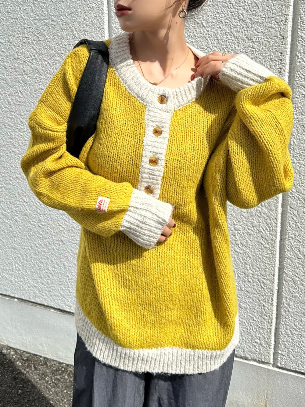 イエロー系のニット/セーター、グレー系のスラックス、ブラック系のハンドバッグを着用したレディースの秋コーディネートの4枚目の写真