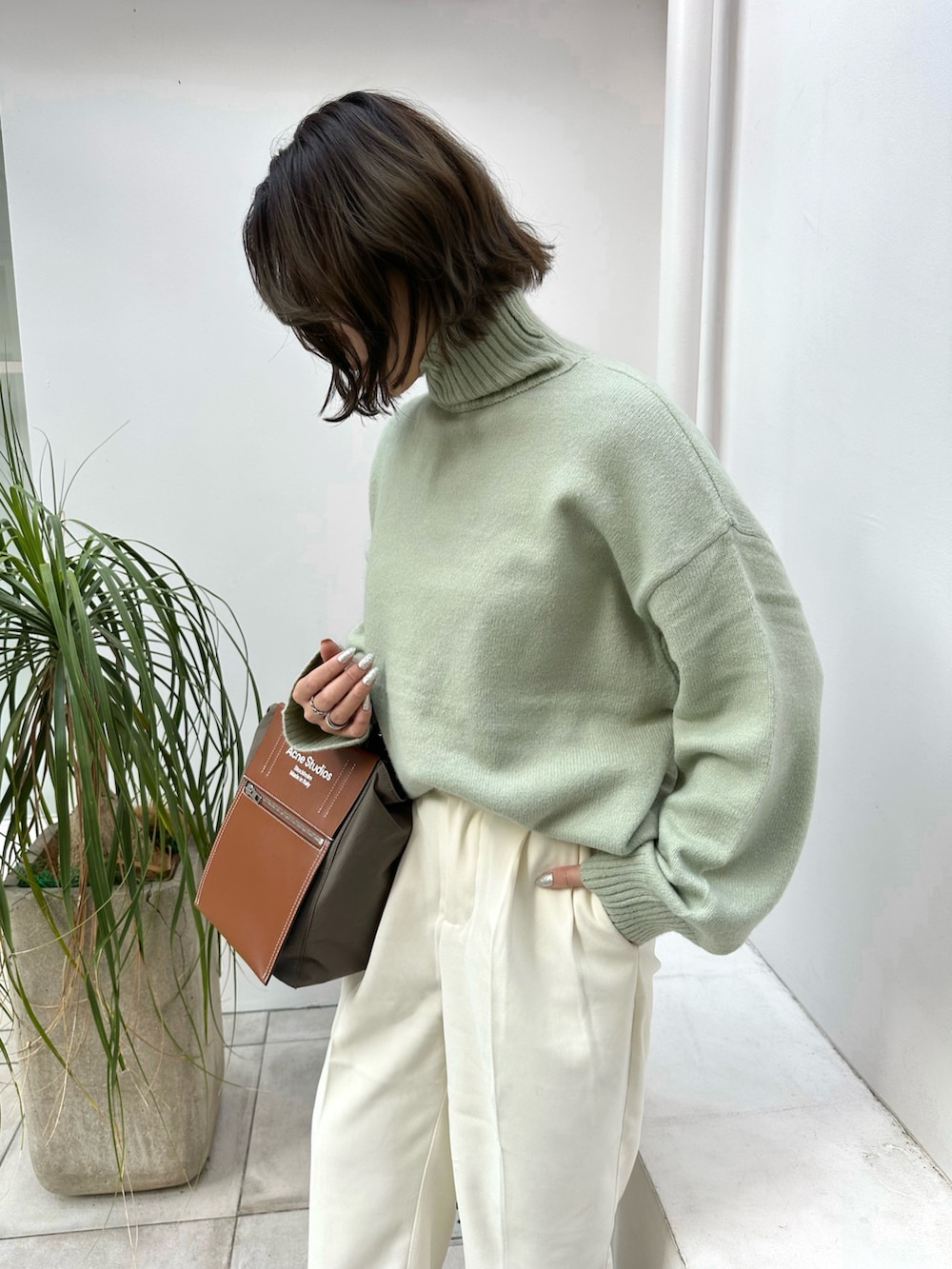 ホワイト系のその他パンツ、グリーン系のニット/セーター、ホワイト系のダウンジャケット/コートを着用したレディースの冬コーディネートの2枚目の写真