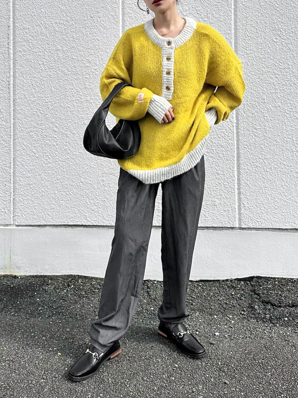 イエロー系のニット/セーター、グレー系のスラックス、ブラック系のハンドバッグを着用したレディースの秋コーディネートの2枚目の写真