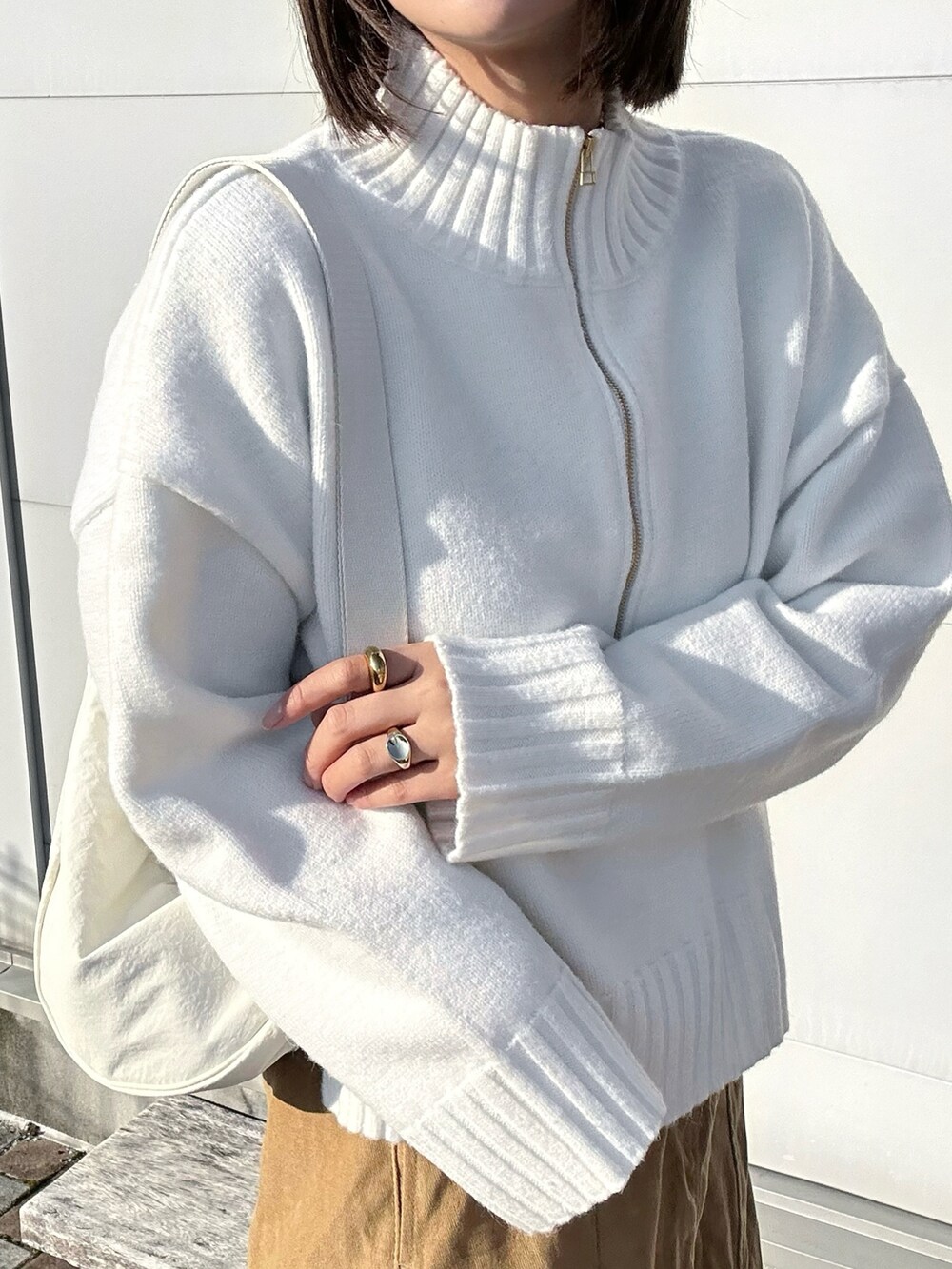 ホワイト系のニット/セーター、ホワイト系のショルダーバッグ、ベージュ系のスニーカーを着用したレディースの冬コーディネートの4枚目の写真