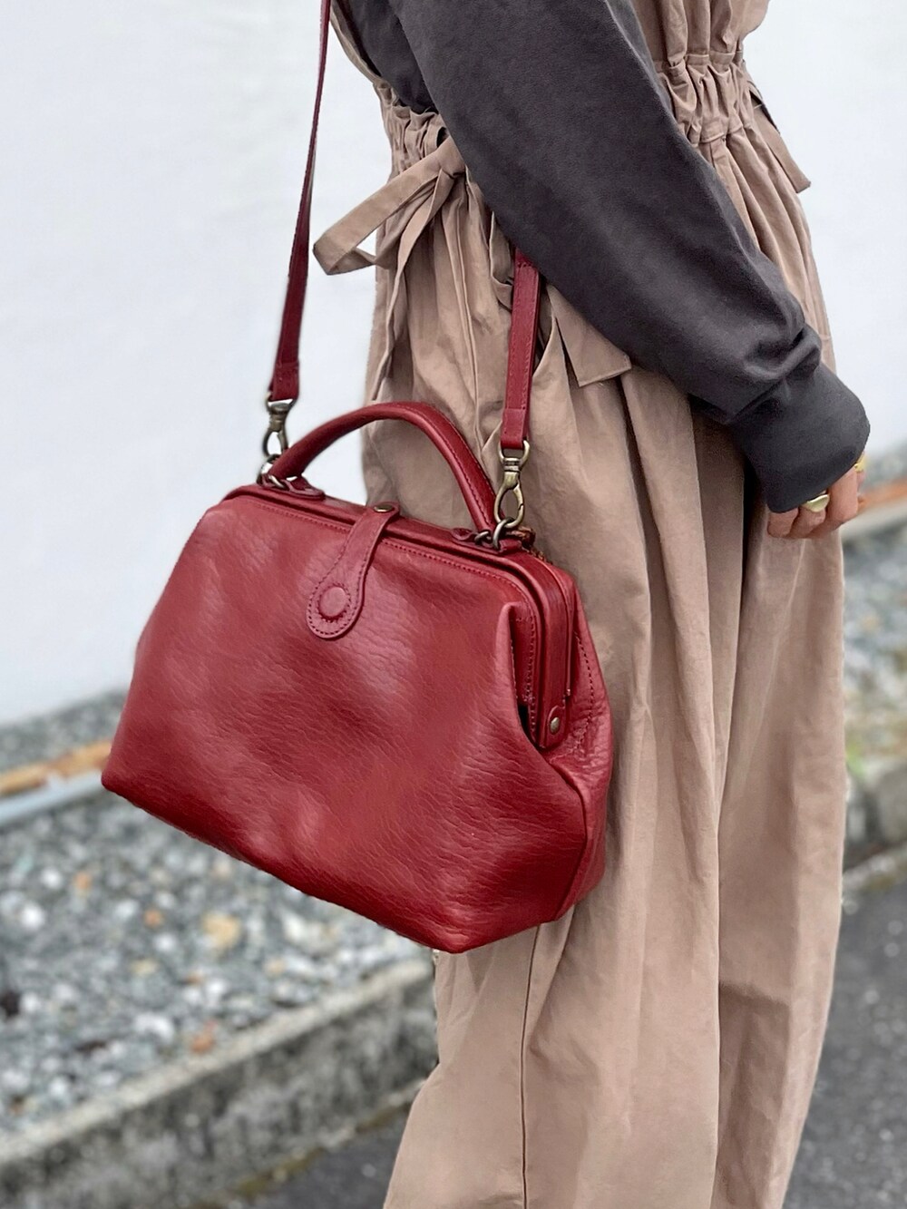 レッド系のショルダーバッグ、ベージュ系のオールインワン・サロペット、グレー系のパンプスを着用したレディースの秋コーディネートの3枚目の写真