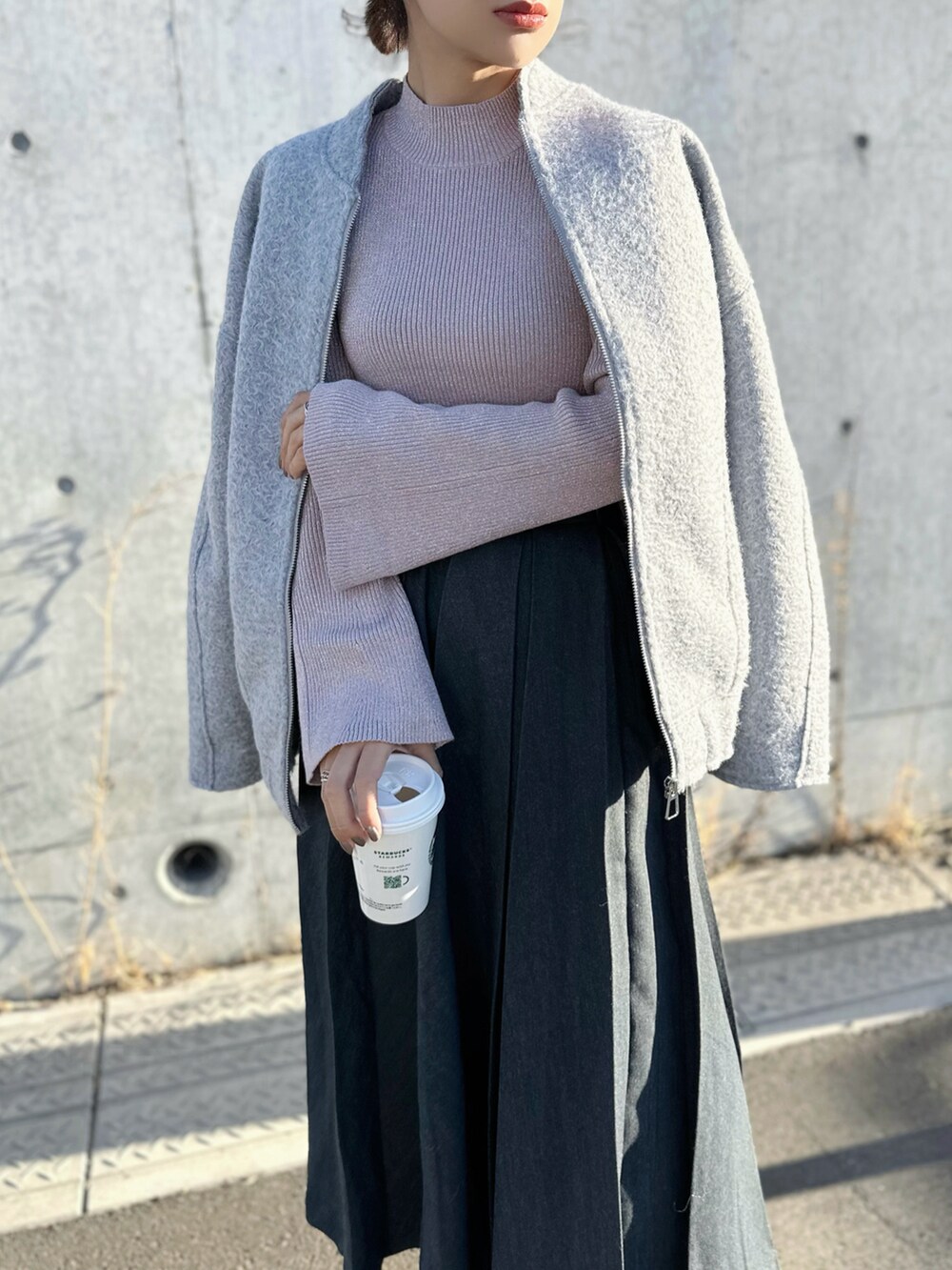 ピンク系のニット/セーター、グレー系のスカート、グレー系のスニーカーを着用したレディースの冬コーディネートの3枚目の写真