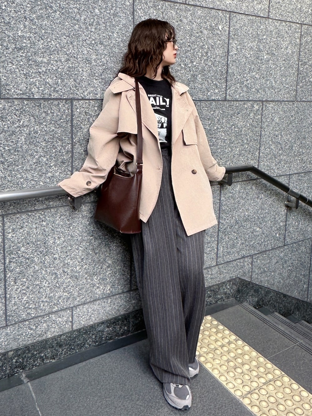 ベージュ系のトレンチコート、ブラック系のTシャツ/カットソー、グレー系のその他パンツを着用したレディースの春コーディネートの5枚目の写真