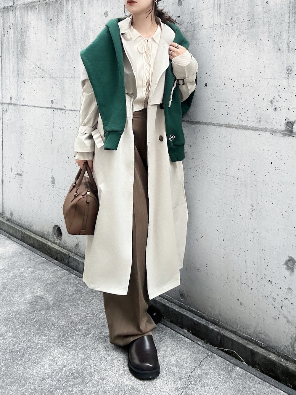 ホワイト系のトレンチコート、ブラウン系のその他パンツ、ホワイト系のニット/セーターを着用したレディースの春コーディネートの2枚目の写真